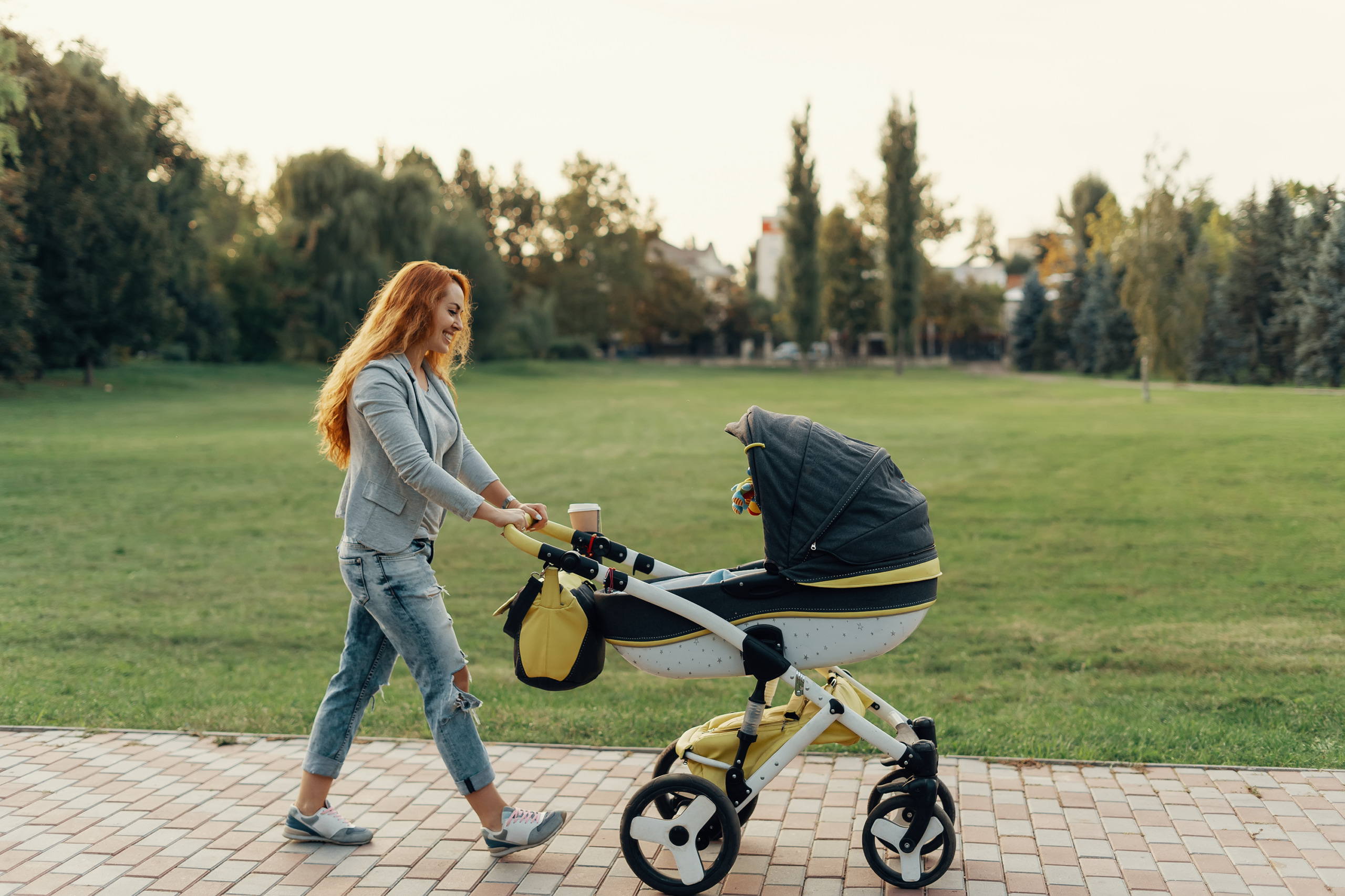 Mother enjoying walk carrying her little child in his baby trolley.